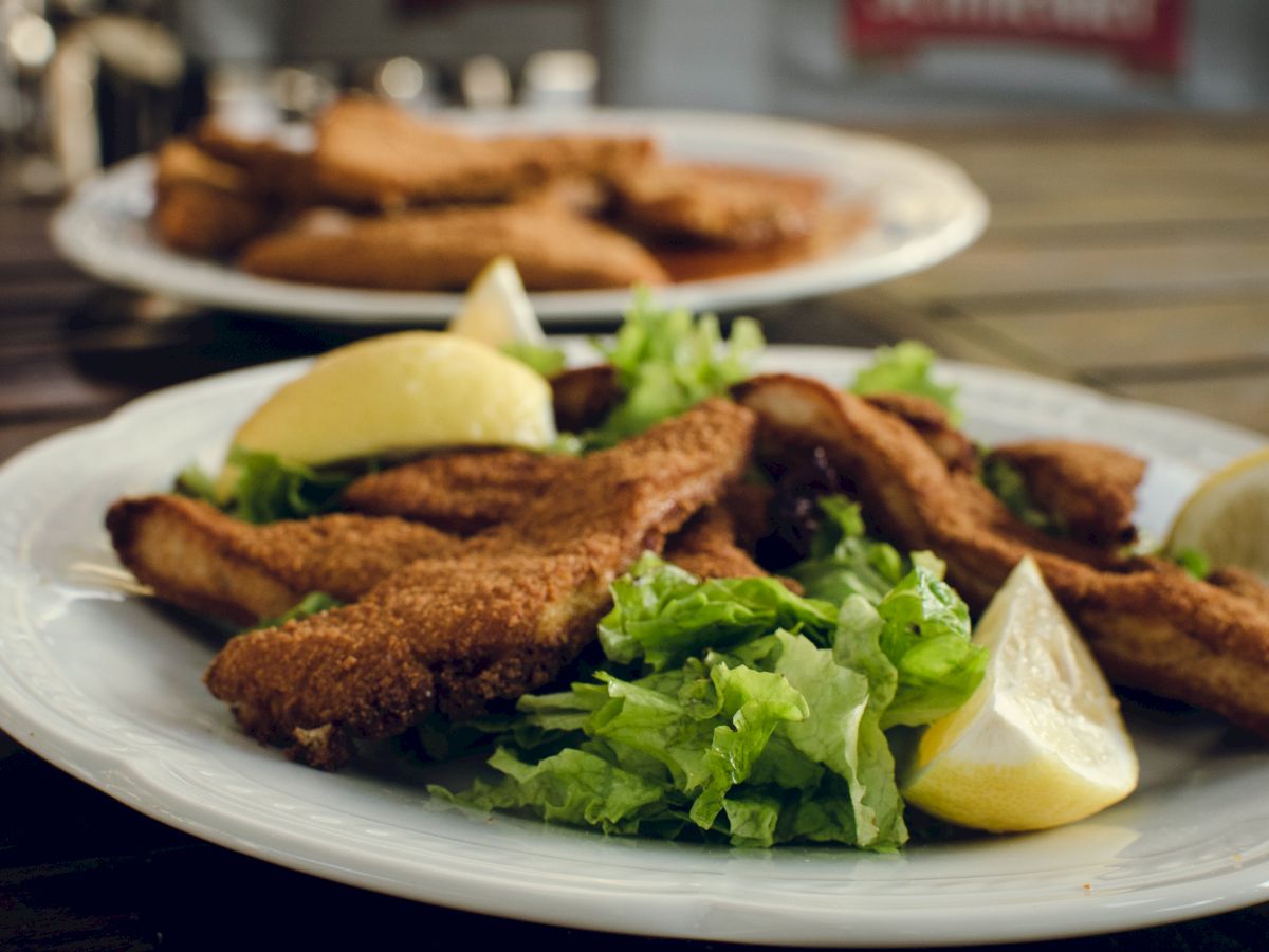 A plate of breaded and fried food, likely fish or chicken, with lemon wedges and lettuce. Appears to be a delicious meal.