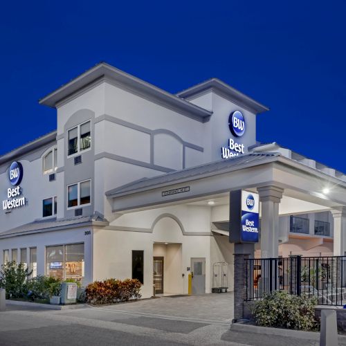 The image shows a building at night labeled "Best Western" with lit signage and surrounding plants, captured under a clear dark blue sky.
