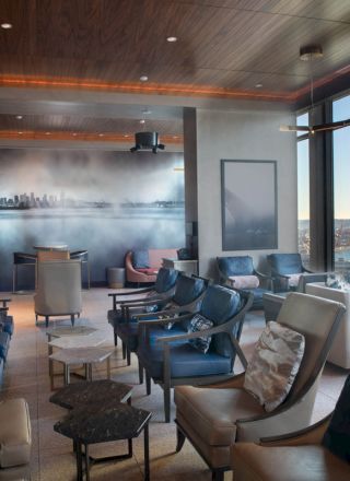 A modern lounge with comfortable seating, a large window with a scenic view, and stylish lighting and decor.